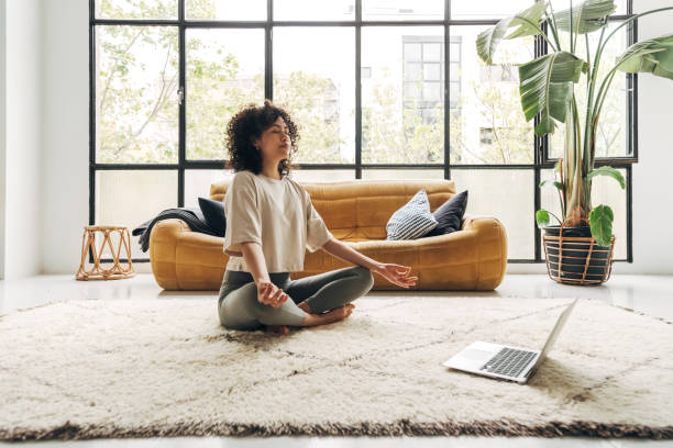 Young Woman Meditating at Home with Online Meditation Lesson via Laptop